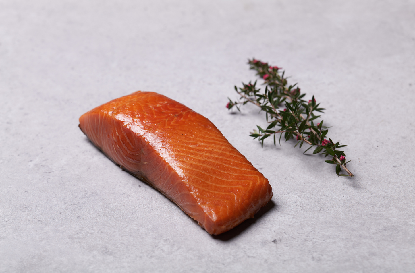 Hot smoked salmon portion unpackaged with manuka branch next to it