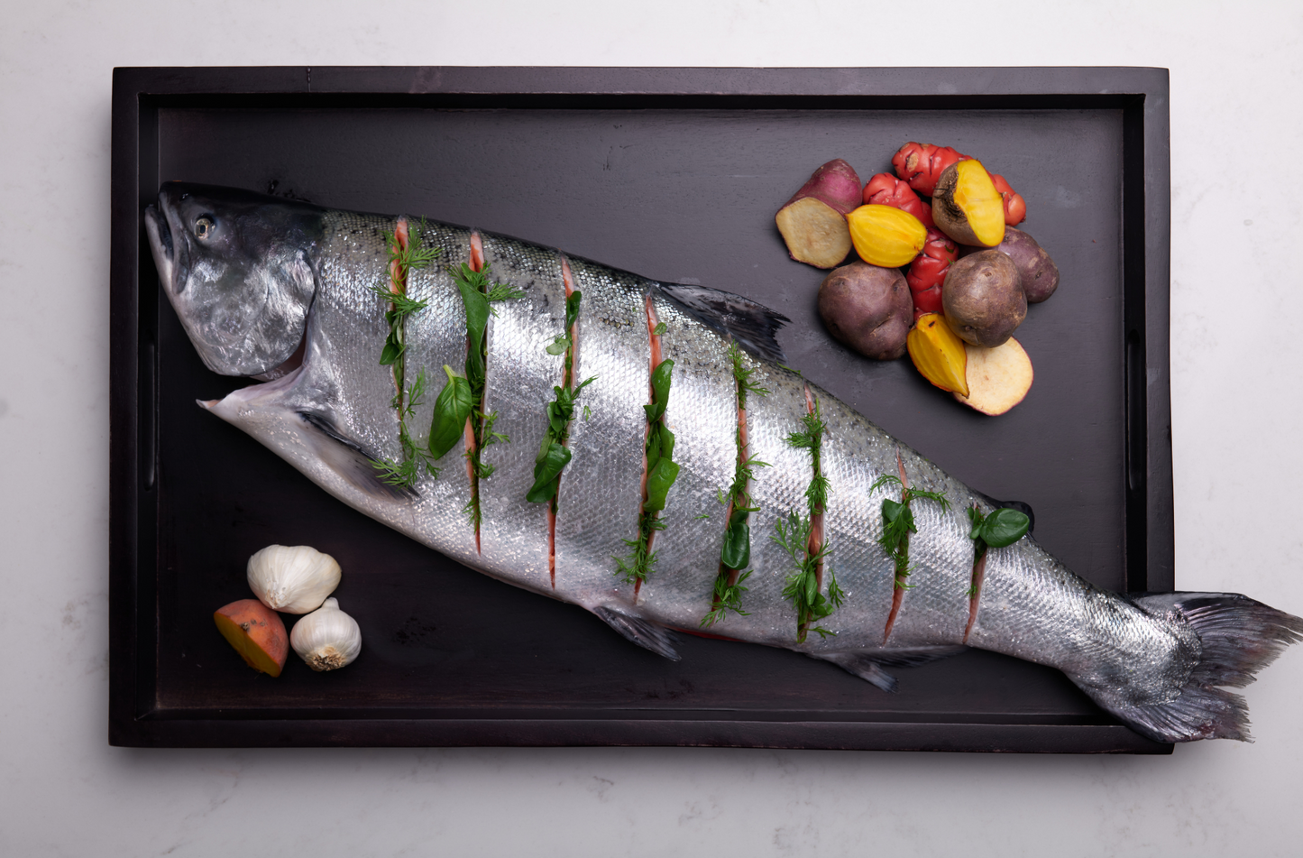 Fresh whole salmon prepped to bake. Salmon has been sliced and lightly stuffed with herbs